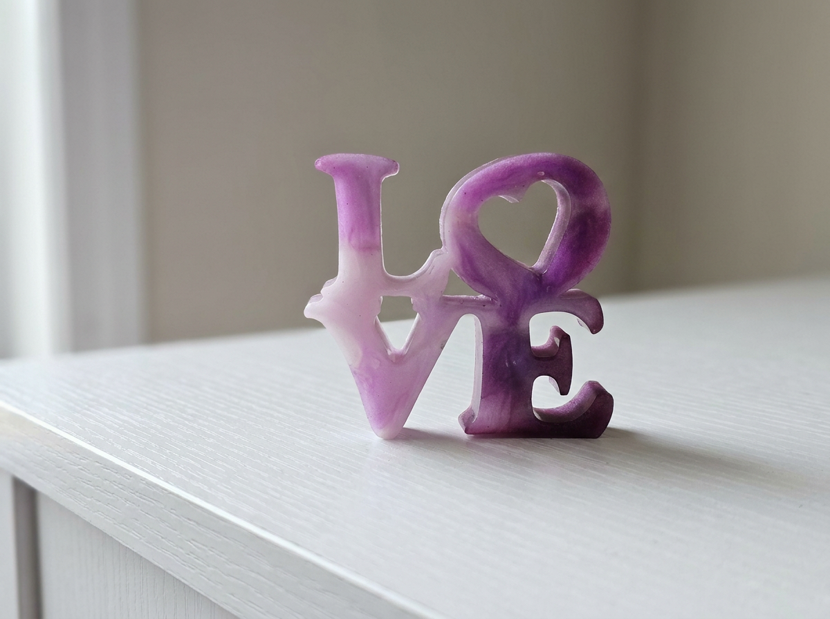 Velvet Alchemy Amethyst Romance LOVE letters in pink-purple resin on a white surface.